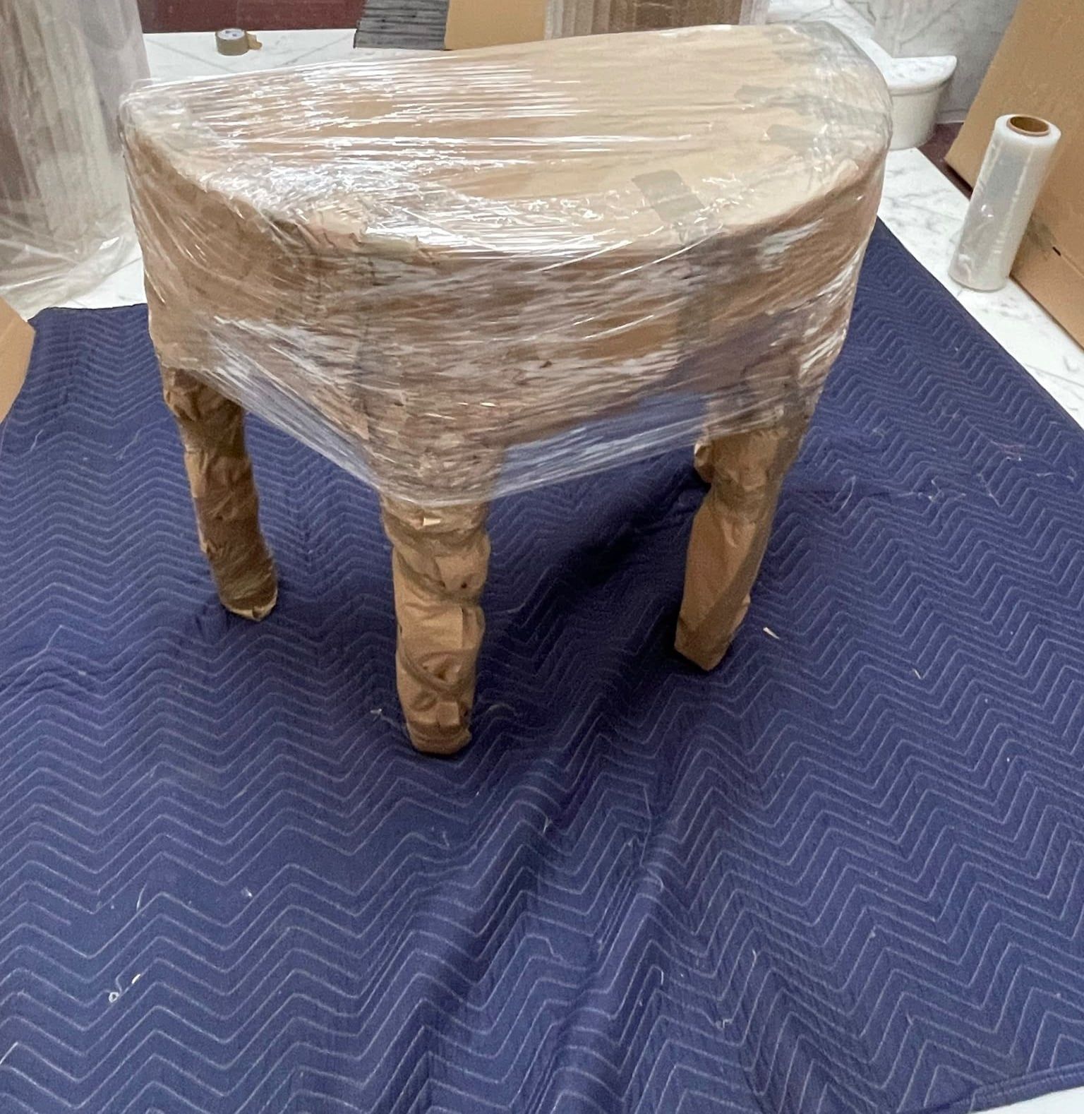 A table wrapped, with its legs padded, on a moving blanket